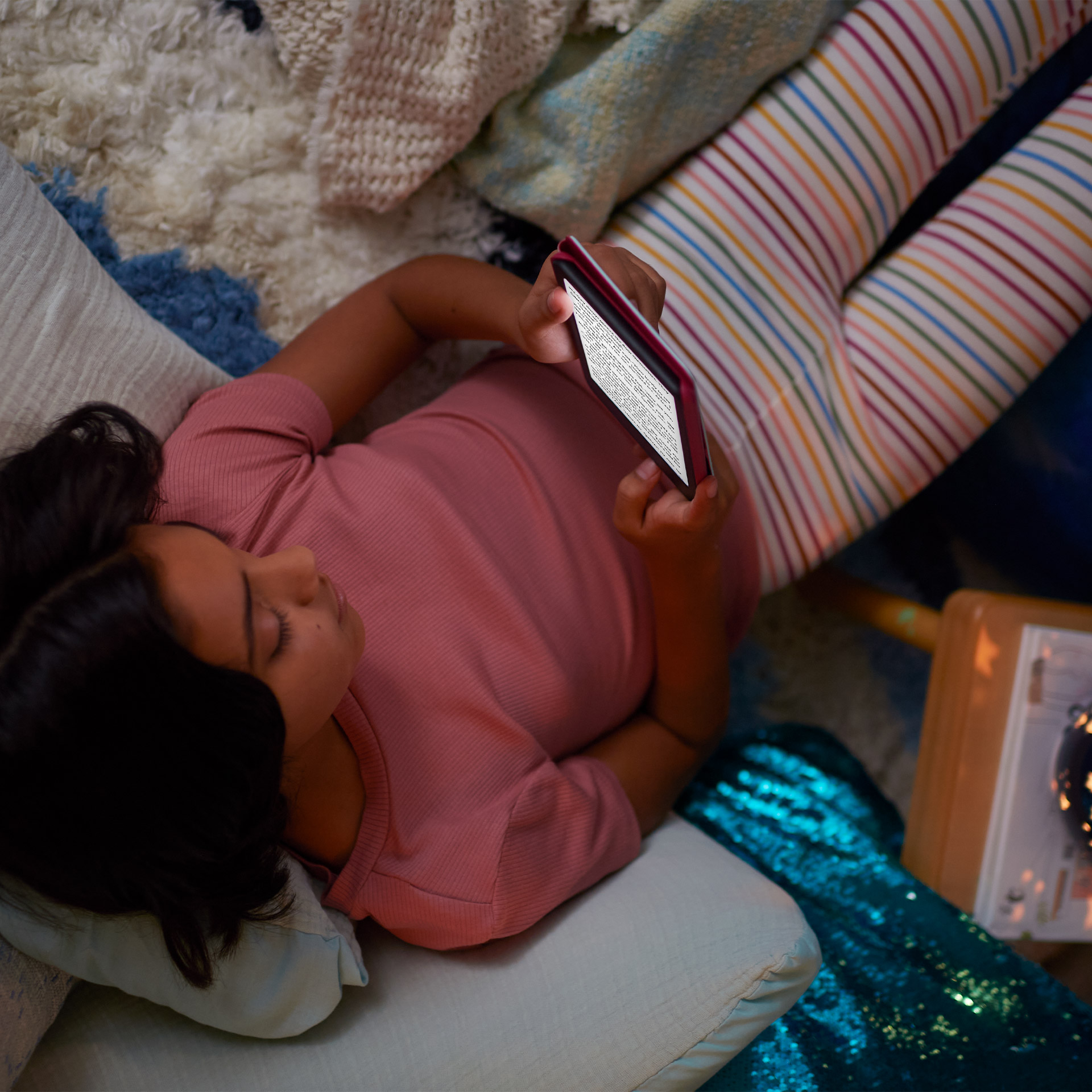 En una habitación poco iluminada, un niño sostiene un Kindle Kids con la pantalla iluminada.